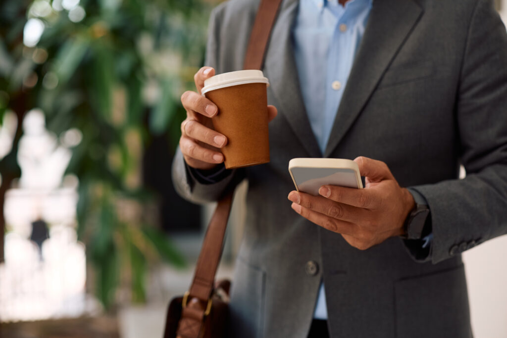 close up of entrepreneur texting on cell phone while having a cup of coffee at work.